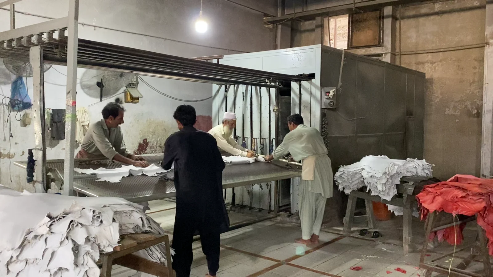 Workers preparing hides on a tannery table