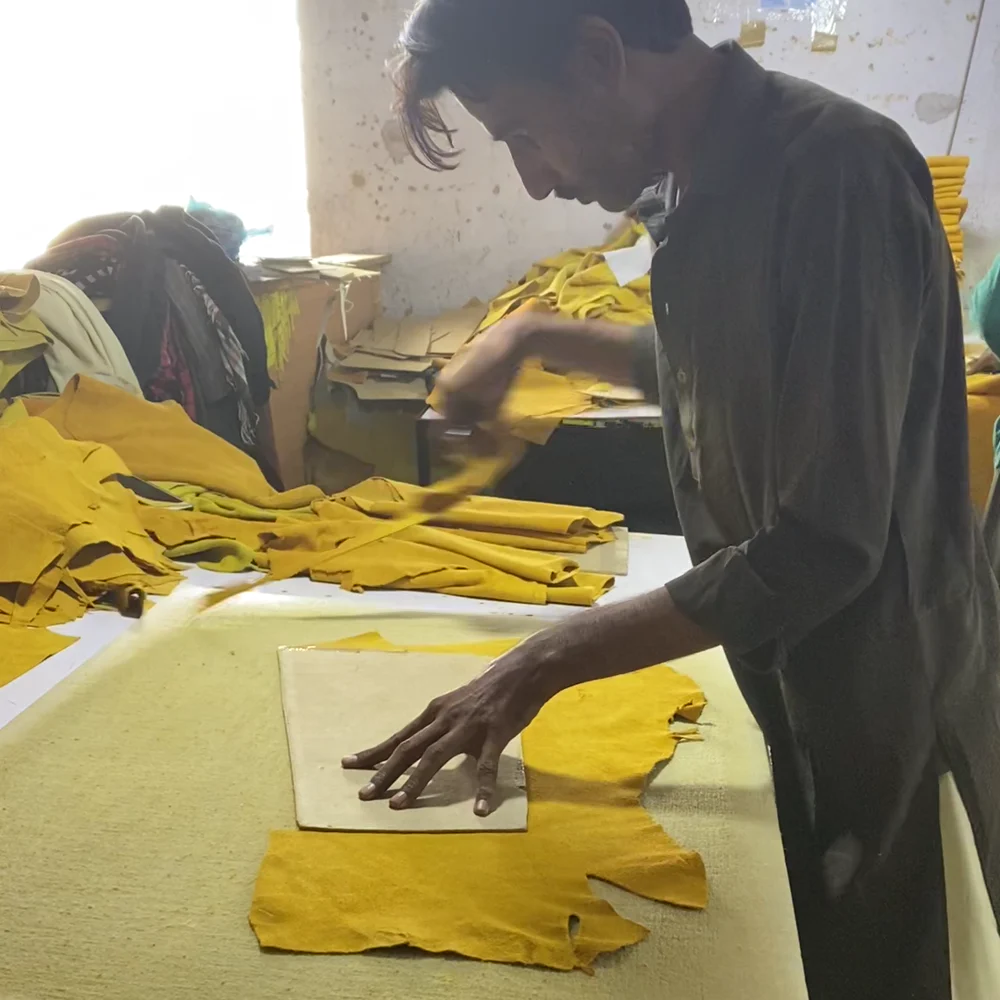 A worker cutting yellow leather against a paper pattern
