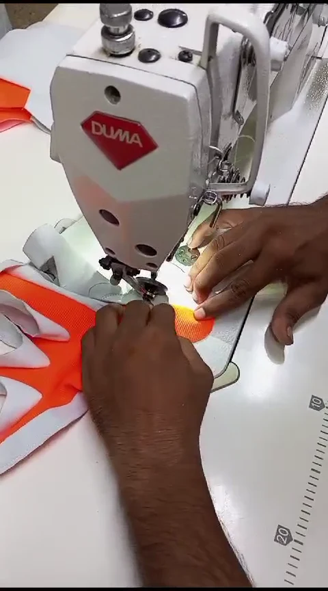 Orange-and-white glove components being stitched