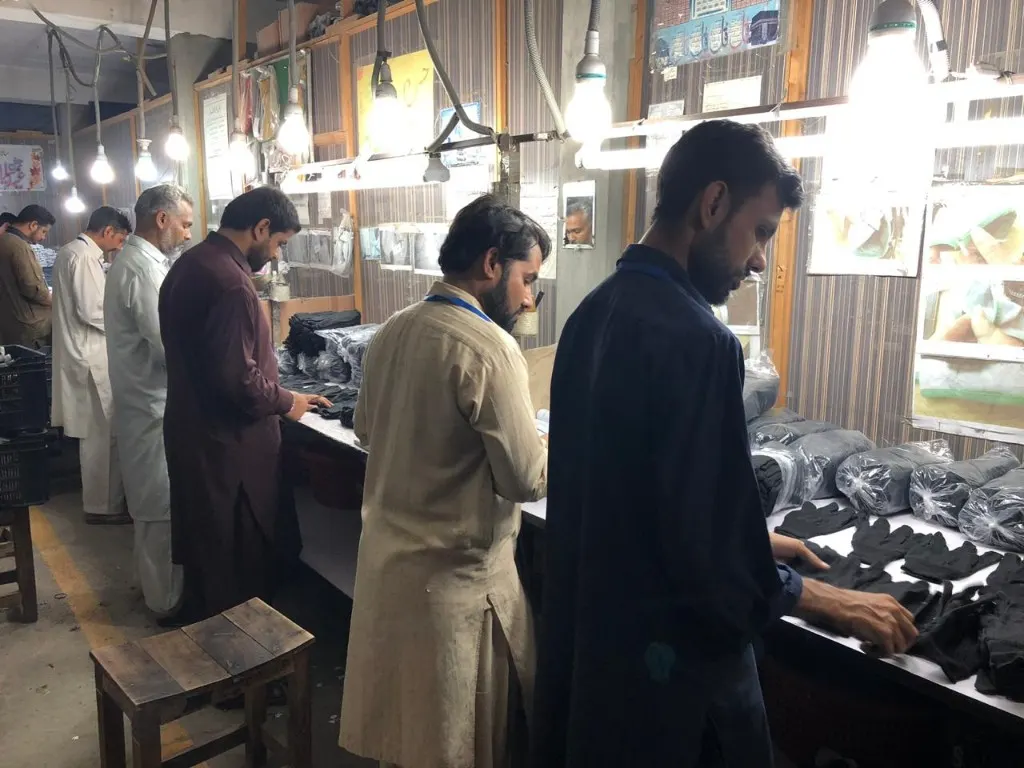 Inspectors reviewing black gloves along a factory inspection line