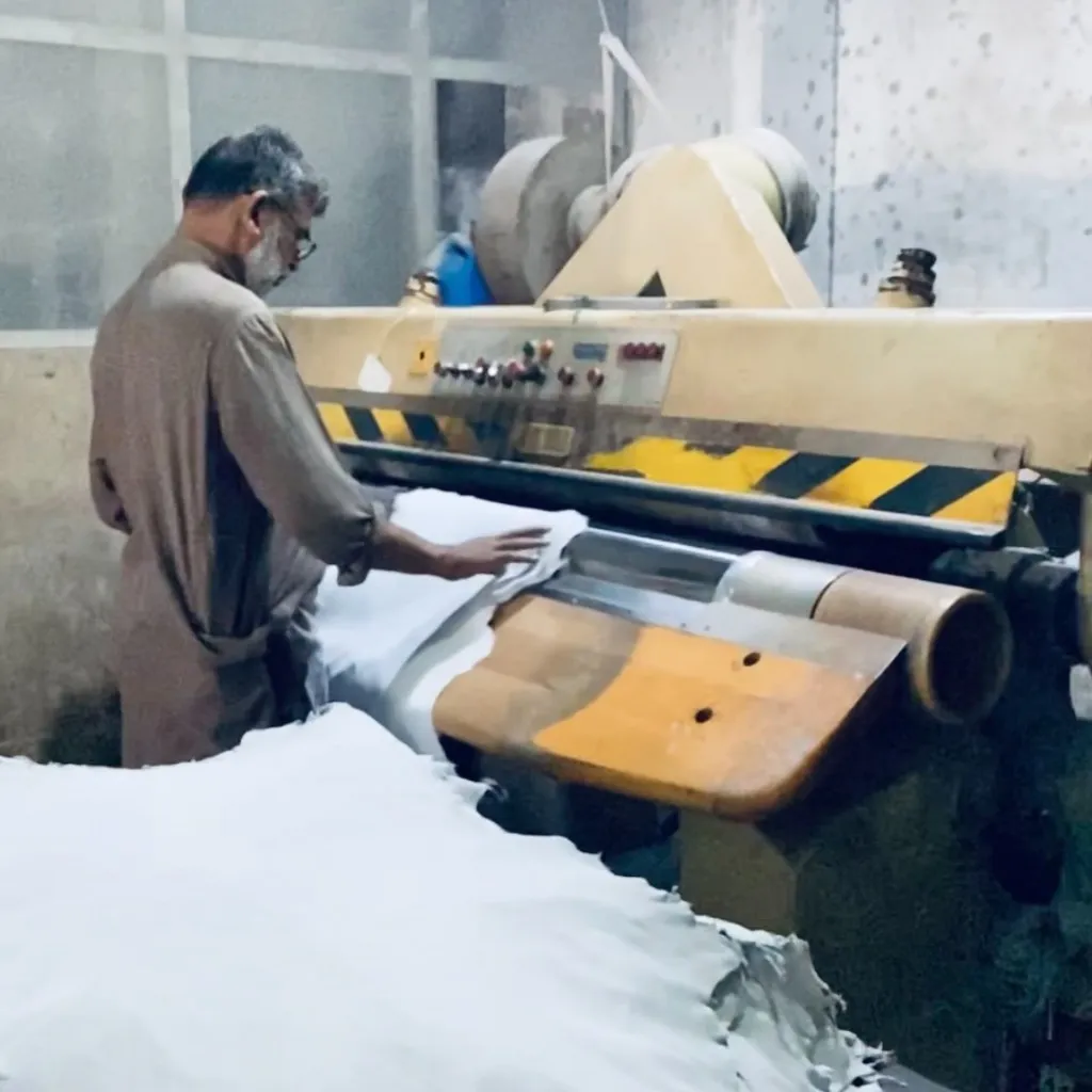 An operator feeding leather through a finishing machine