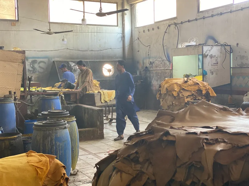 Workers sorting hides beside stacks of leather in the tannery
