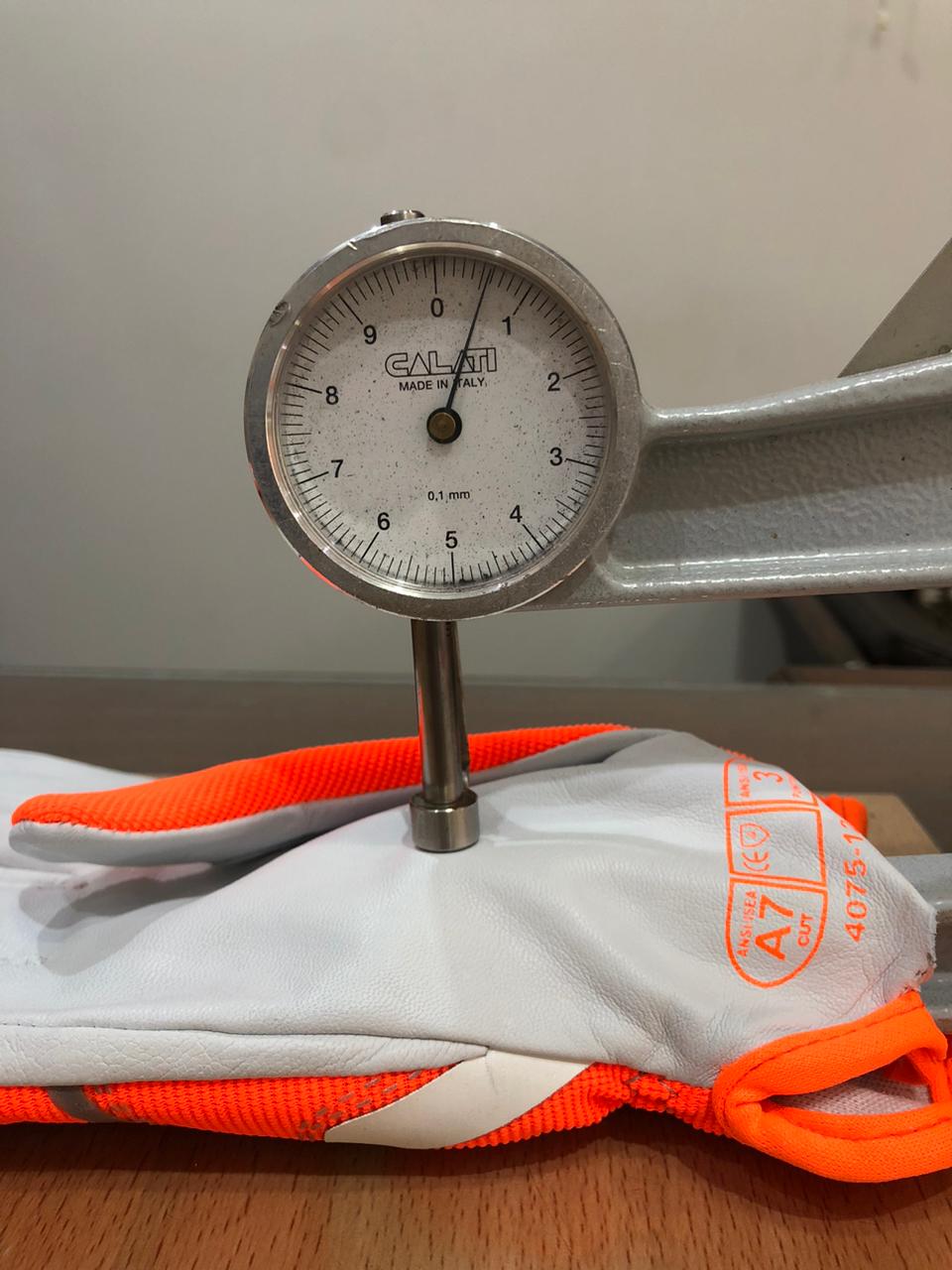 A thickness gauge measuring the leather on a glove sample